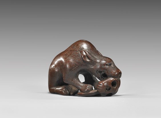ANTIQUE WOOD NETSUKE: Wolf Biting Skull: ANTIQUE WOOD NETSUKE: Wolf Biting Skull Antique wood carved wood netsuke; of a wolf with inlaid eyes, hunched over and biting a skull; signed Shuho or Ryoshu, early 19th Century 木根ߢ