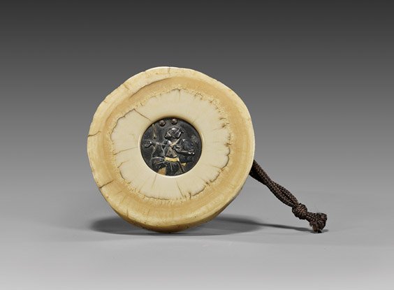 ANTIQUE NARWHAL IVORY MANJU NETSUKE: ANTIQUE NARWHAL IVORY MANJU NETSUKE Rare and antique, narwhal ivory kagamibuta manju netsuke; the small inset mixed metalwork plate depicting a juggler; unsigned, 19th Century 象牙饅