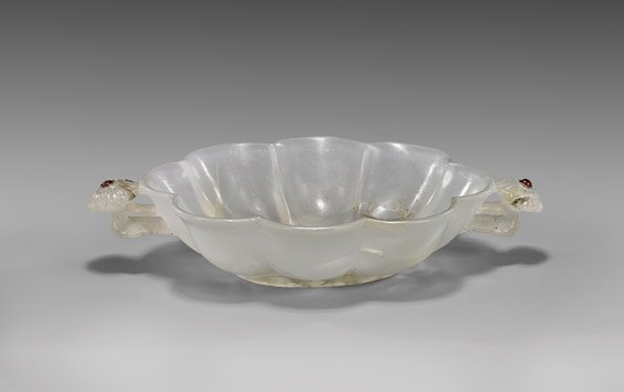 MOGHUL-STYLE CARVED AGATE BOWL: MOGHUL-STYLE CARVED AGATE BOWLRare Moghul-style carved chalcedony agate bowl; of lobed, foliate form, with two circular floral handles each set with a small ruby; the stone of nearly transparent grayi