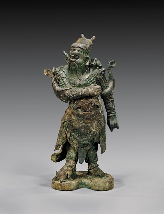 MING DYNASTY BRONZE GUARDIAN FIGURE: 銅雕護衛人物 MING DYNASTY BRONZE GUARDIAN FIGURE Chinese Ming Dynasty, bronze guardian figure; standing in finely detailed armor, with a qilin pup at his feet; H: 1