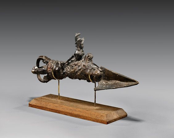 ANTIQUE TIBETAN OR NEPALESE BRONZE DEITY: 藏傳/尼泊爾銅雕人物 ANTIQUE TIBETAN OR NEPALESE BRONZE IMPLEMENT Antique Tibetan or Nepalese bronze implement of a phurba; depicted with a deity r
