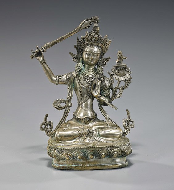 Nepalese or Sino-Tibetan Silvered Bronze Deity: Nepalese or Sino-Tibetan Silvered Bronze Deity Nepalese or Sino-Tibetan silvered bronze figure of Manjushri; seated on a lotus pedestal in lotus posture: with one hand in mudra and holding a flower, t