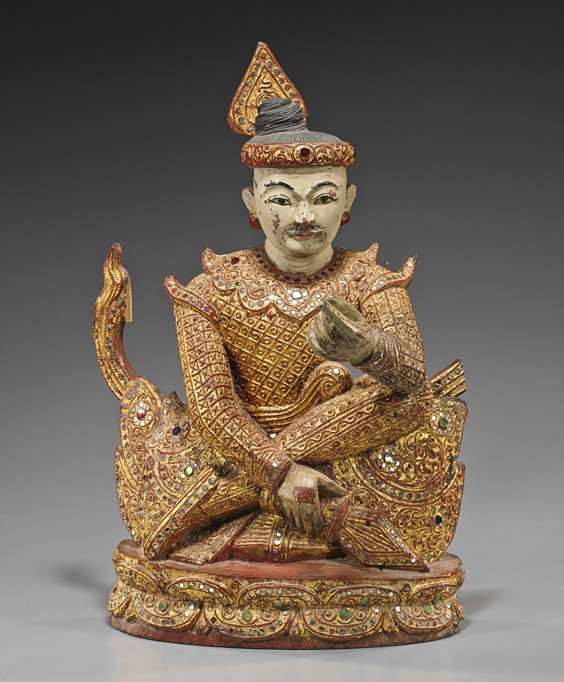 Antique Southeast Asian Carved Wooden Figure: Antique Southeast Asian Carved Wooden Figure Antique Southeast Asian (probably Thai), carved and polychromed wood figure; in a seated position, elaborately decorated gilt and "jeweled" man atop a "cus