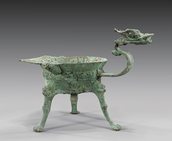 EASTERN HAN DYNASTY BRONZE VESSEL: 青銅雕龍首三足器 EASTERN HAN DYNASTY BRONZE VESSEL Archaic Chinese, Eastern Han Dynasty bronze vessel; of a tripod brazier/lamp (jiao dou), with a detai