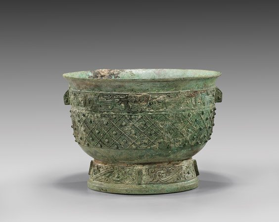 IMPORTANT ARCHAIC BRONZE YU VESSEL: 青銅動物紋容器 IMPORTANT ARCHAIC BRONZE YU VESSEL Important archaic Chinese, early Western Zhou Dynasty, bronze vessel (yu) vessel; of bucket form set on a ta