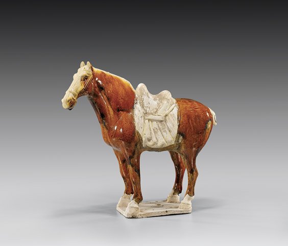 TANG DYNASTY GLAZED POTTERY HORSE: 釉陶馬俑 TANG DYNASTY GLAZED POTTERY HORSEChinese Tang Dynasty, glazed pottery model of a horse; with amber body and straw glaze to head: standing four-square and with nicely m