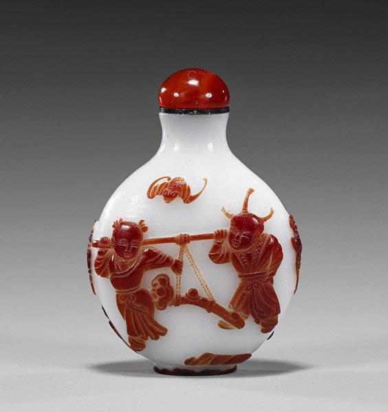 Carved Red Glass Overlay Snuff Bottle: Boys: Carved Red Glass Overlay Snuff Bottle: Boys Carved overlay red glass snuff bottle; of footed circular form, decorated with jubilant young boys carrying a ruyi scepter, flanked by bats, carnelian agate