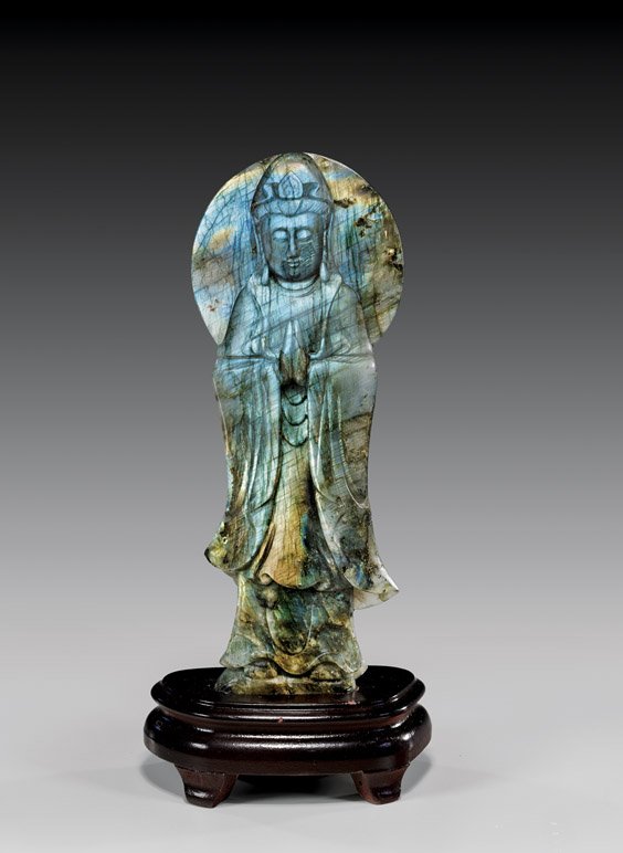 LABRADORITE GUANYIN CARVING: LABRADORITE GUANYIN CARVING The goddess of compassion stands serenely with her hands together in prayer against a large halo disc. She has been finely fashioned from a single first-class piece of labr