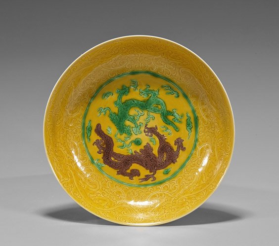 Yongzheng-Style Yellow Porcelain Dragon Dish: Yongzheng-Style Yellow Porcelain Dragon DishYongzheng-style yellow porcelain dish; of shallow circular form with raised foot, incised writhing dragons to interior and exterior, the center with two con