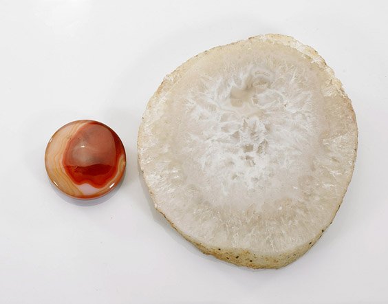 Two Polished Minerals: Agate & Quartz: Two Polished Minerals: Agate & Quartz Two polished circular minerals: carnelian agate circular form with attractive banding, pierced for stringing; together with clear crystal quartz slice; D: 4 1/2" 
