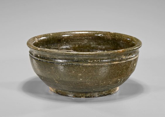 Han Dynasty Brown Glazed Pottery Bowl: Han Dynasty Brown Glazed Pottery Bowl Han Dynasty brown glazed pottery bowl; of simple circular form, the foot left unglazed and with nice combing marks (chips and usual wear); D: 7 1/2"