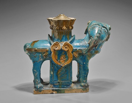 Ming Dynasty Blue Earthenware Elephant: Ming Dynasty Blue Earthenware ElephantChinese Ming Dynasty, blue glazed earthenware model of a stylized elephant; standing four-square looking towards the right, saddle with lingzhi emblems on each si