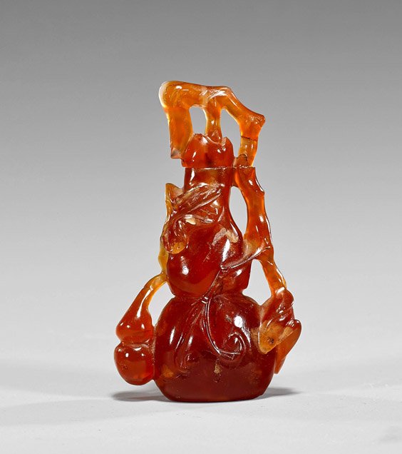 Carved Carnelian Snuff Bottle: Gourd: Carved Carnelian Snuff Bottle: Gourd Carved carnelian snuff bottle; of gourd form with meandering vines, with pale orange suffusions and natural inclusions (stopper glued, usual wear); H: 2 3/4"