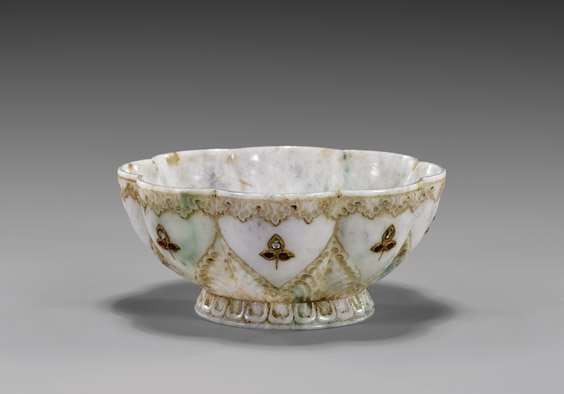 CARVED JADEITE MUGHAL-STYLE BOWL: 痕都斯坦式花形碗 CARVED JADEITE MUGHAL-STYLE BOWL Carved jadeite Mughal-style bowl; of footed lobed form with scalloped rim, the exterior with foliate d