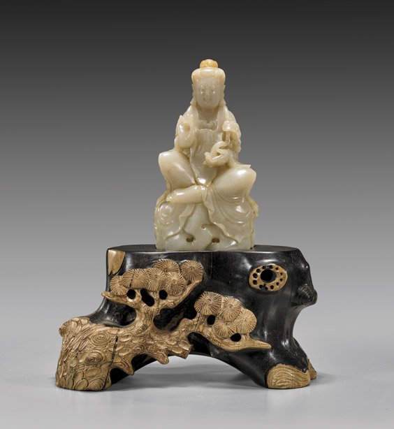 CARVED WHITE JADE GUANYIN: 白玉雕觀音擺件 CARVED WHITE JADE GUANYIN Chinese carved white jade figure; of Guanyin holding a ruyi scepter in one hand, the other in mudra; and seated atop 