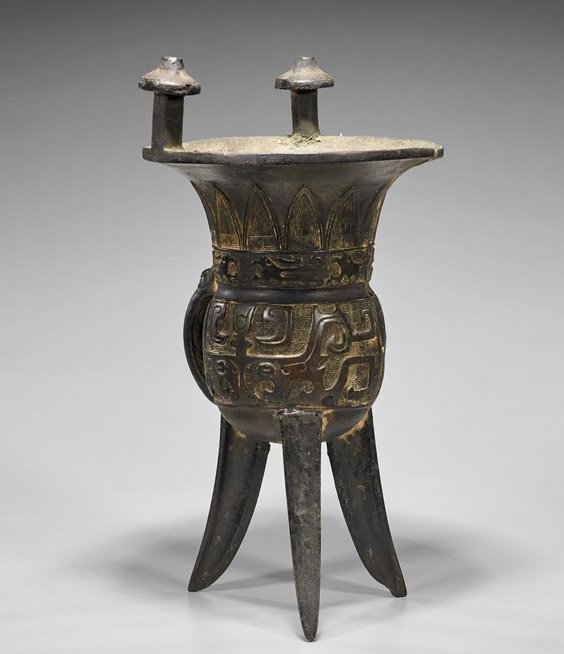 Antique Shang-Style Bronze Tripod Vessel (Jia): Antique Shang-Style Bronze Tripod Vessel (Jia) Antique Chinese Shang-style bronze tripod vessel (jia); raised on three-blade supports with dragon head handle and a pair of capped posts rising from the