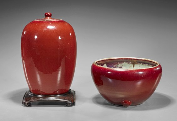 Two Chinese Ox-Blood Porcelains: Two Chinese Ox-Blood Porcelains Two Chinese ox-blood red glazed porcelains: circular tapering towards the base with three knobs at base; together with tall ovoid form covered vase with knob finial (so