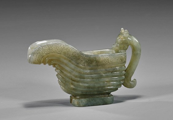 Chinese Carved Celadon Jade Libation Cup: Chinese Carved Celadon Jade Libation Cup Chinese Ming-style, carved greenish celadon jade libation cup; with incised meandering pattern at the rim and hydra handle, 17th Century-style; L: 4 3/4"