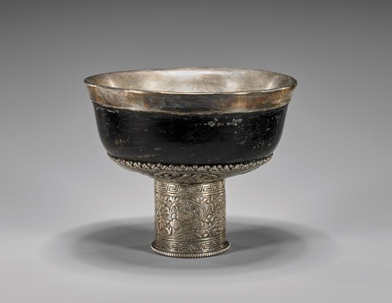 ANTIQUE TIBETAN WOOD & SILVER WINE CUP: ANTIQUE TIBETAN WOOD & SILVER WINE CUP Antique Tibetan wine cup; wood body with sterling silver lining and mount; the support and underside with engraved Buddhist emblems and flowers, 19th Century; D: