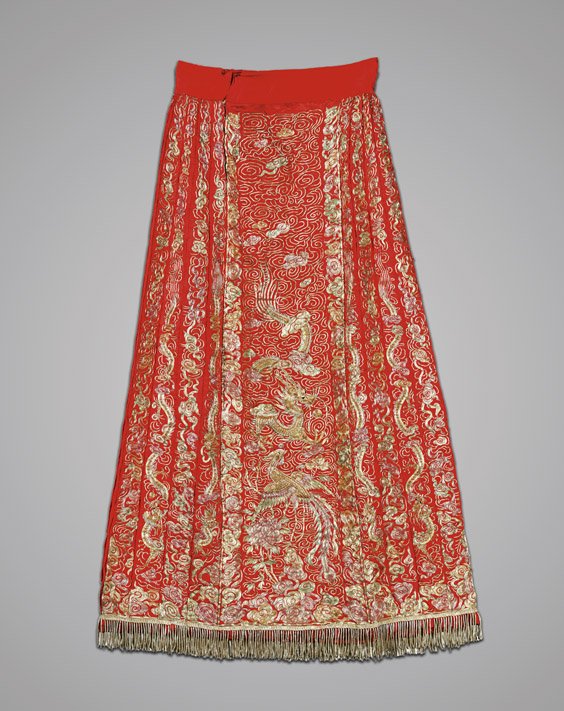 CHINESE EMBROIDERED RED SILK SKIRT: CHINESE EMBROIDERED RED SILK SKIRT Elaborately embroidered, Chinese silk skirt; the front and verso with design of couched dragon and phoenix in gilt metal thread, flanked by rows of billowing clouds,