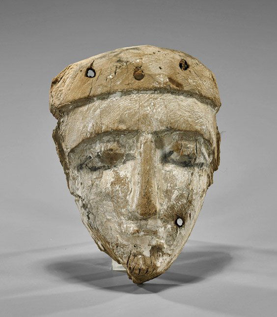 Egyptian Gesso-Painted Wood Mummy Mask: Egyptian Gesso-Painted Wood Mummy MaskAnicent Egyptian gesso-painted and carved wood mummy mask; the triangular face in white with eyes and brows in black, a slender nose and small lips (drilled for a