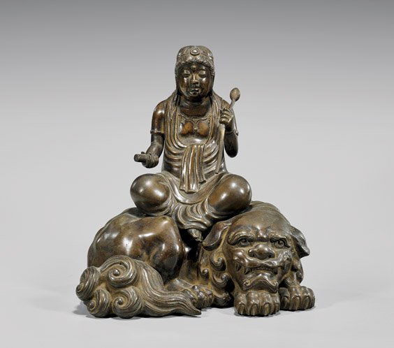 ANTIQUE JAPANESE BRONZE KANNON ON SHI-SHI: ANTIQUE JAPANESE BRONZE KANNON ON SHI-SHIAntique Japanese bronze sectional figural group; of Kannon holding a single separate lotus bud; a scroll in her other hand; and seated upon a recumbent Shi-shi