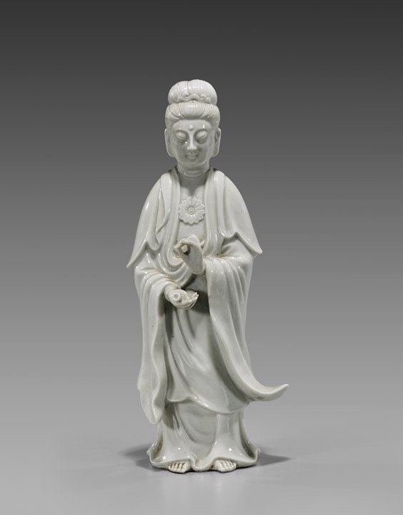 ANTIQUE BLANC DE CHINE GUANYIN: ANTIQUE BLANC DE CHINE GUANYIN Antique Chinese blanc de chine porcelain figure; of Guanyin, with appliqué blossom to her chest, standing in flowing robes and pouring out her bottle of tears, Circa 19
