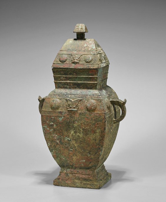 Tall Shang-Style Bronze Wine Vessel: Large Chinese Shang-style bronze wine vessel (lei); of tapered form on a square base with handles and fitted roof-like cover; with bosse and mask bands;; H: 18 1/4"