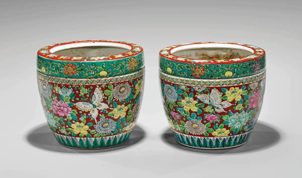 PAIR ANTIQUE ENAMELED PORCELAIN JARDINIÈRES: Pair of antique Chinese enameled porcelain jardinières; each cylindrical form with design of butterflies amid colorful flowers, on tomato red grounds, with patterned bands above and below; Prov