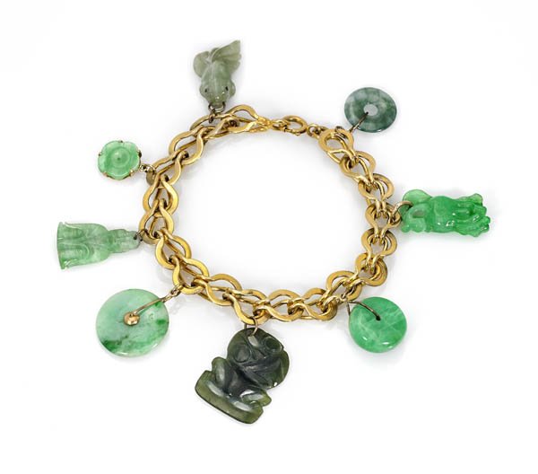 18K GOLD & JADE CHARM BRACELET: 18K yellow gold bracelet of unique, large woven chain links; pending seven vintage and antique Chinese carved jadeite charms, each with some apple green coloration: roundel bead, two bi disc, blossom,