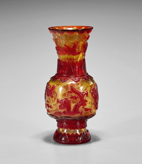 Beijing Glass Red Overlay Vase: Chinese Beijing glass red overlay vase; of yellow speckeled ground and carved red dragons and phoenixes on the bulboud body, with palm leaves on the extended base and neck; seal mark; H: 9 1/4"