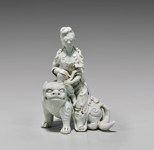 ANTIQUE BLANC DE CHINE GUANYIN: Antique and finely detailed, Chinese blanc de chine porcelain figure; of Guanyin draped in beaded garlands and holding a scepter, seated atop a Fo lion; H: 8 3/4"