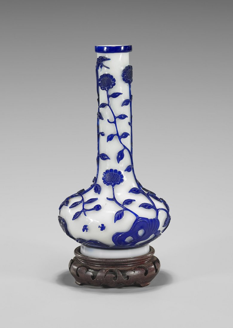 OLD CHINESE OVERLAY GLASS BOTTLE VASE: Old Chinese Beijing overlay glass bottle vase; with design of meandering foliate vines and flowers, with birds, moths and rockery, in deep cobalt blue on milky white ground; Provenance: From the Colle