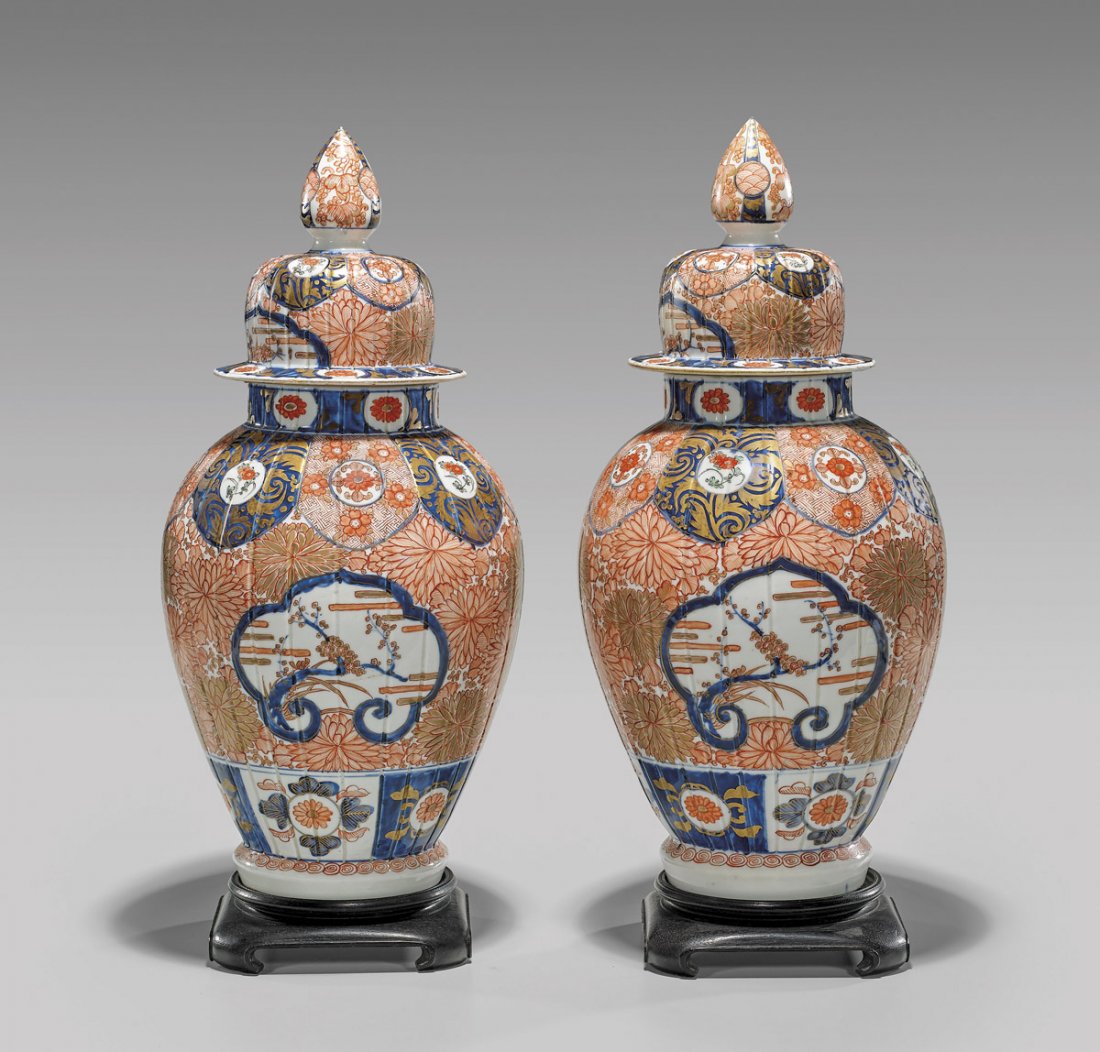 PAIR ANTIQUE JAPANESE IMARI PORCELAIN JARS: Pair of antique, Japanese Imari enameled porcelain covered vases; each of channeled ovoid form, with tall domed cover and drop-shape finials; each decorated with cloud shape panels of blossoming branc