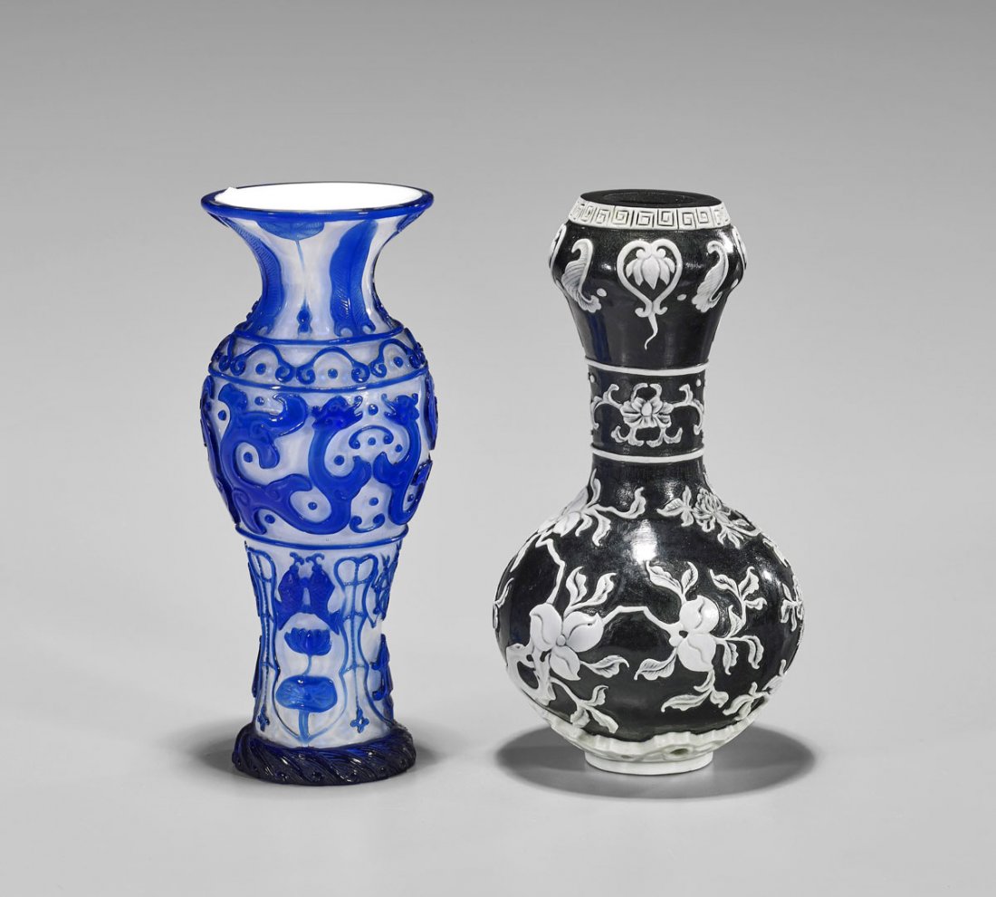 Two Chinese Beijing Glass Vases: Two Chinese carved Beijing glass vases: blue overlay dragons, fish and Buddhist emblems on a white ground; together with white overlay flora on a black ground; H: 6 1/2" (each, approx.)