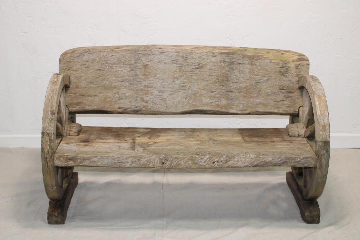 Vintage wagon wheel bench in teak: Outdoor sun-bleached teak bench with wagon wheel sides