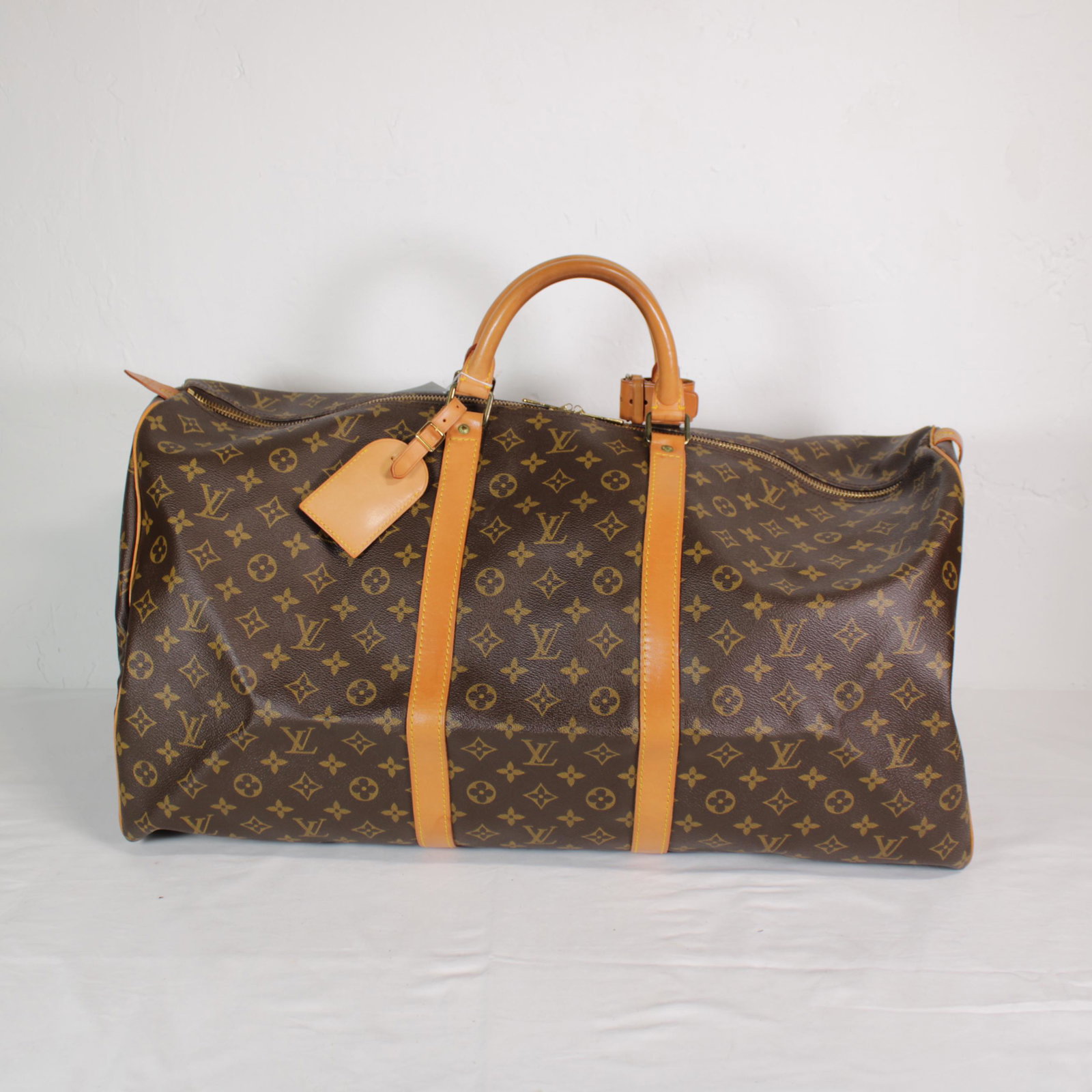 Louis Vuitton Keepall 60 in Monogram Canvas: Genuine Pre-Owned Louis Vuitton Keepall 60 in Brown Monogram Canvas in A condition. Date Code is MI874 This lot includes Luggage Tag, Handle Strap. Measurements: 60*26*31cm (Length * Height * Width). 