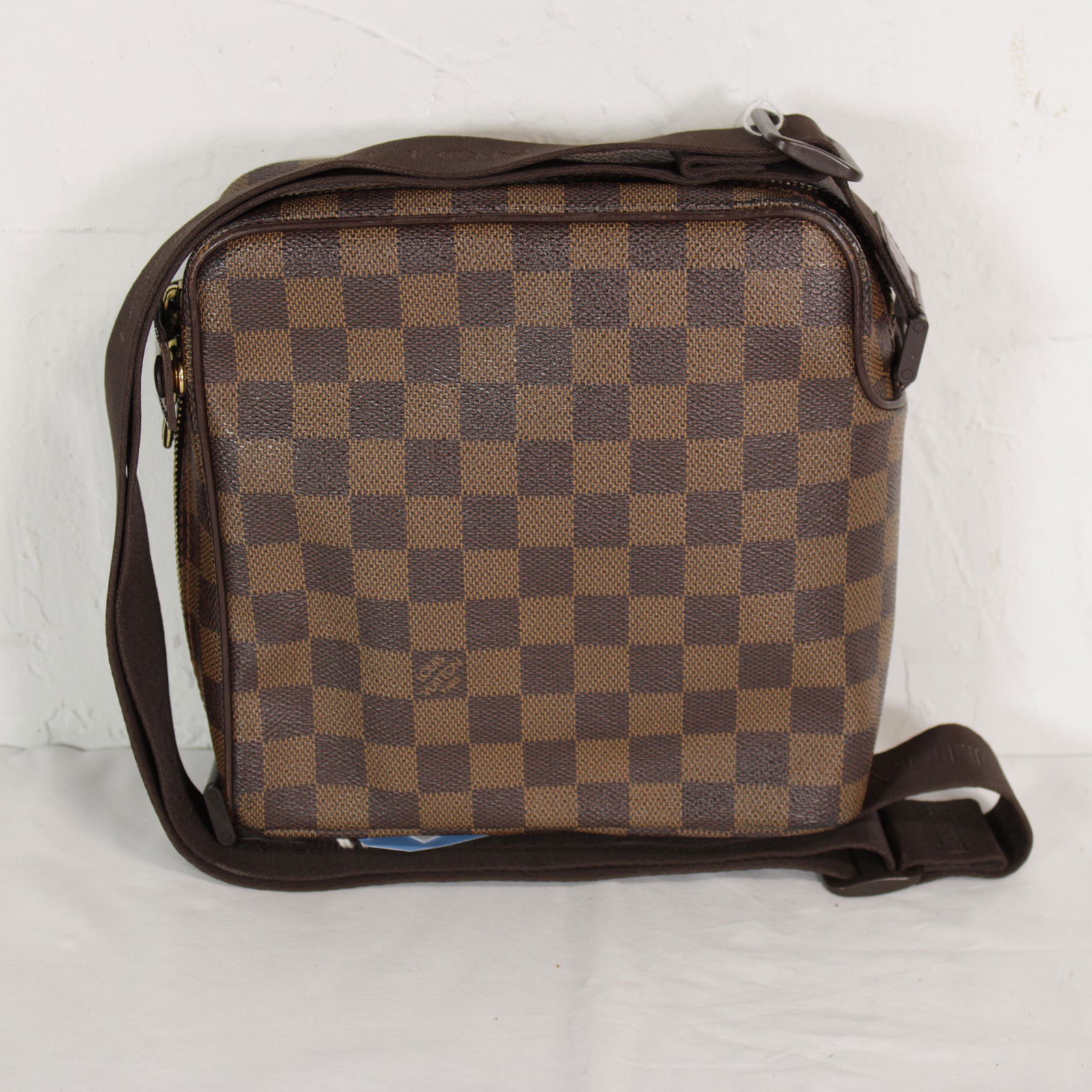 Louis Vuitton Olav PM in Damier Ebene: Genuine Pre-Owned Louis Vuitton Olav PM in Brown Damier Ebene in A condition. Date Code is MI0044. Measurements: 19*19,5*8cm (Length * Height * Width). This lot includes a certificate of authenticity.