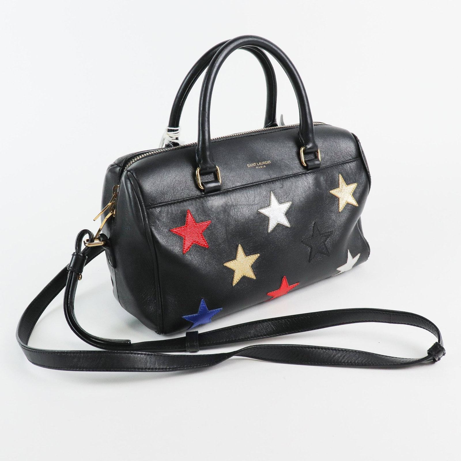 Yves St-Laurent Baby Duffle - Black Leather Multicolor: Genuine Pre-Owned Yves St-Laurent Baby Duffle in Black Multicolor Stars Embellished Leather in A condition. Date Code is VLR332423-0215 This lot includes the following accessories: Dustbag, Strap. Mea