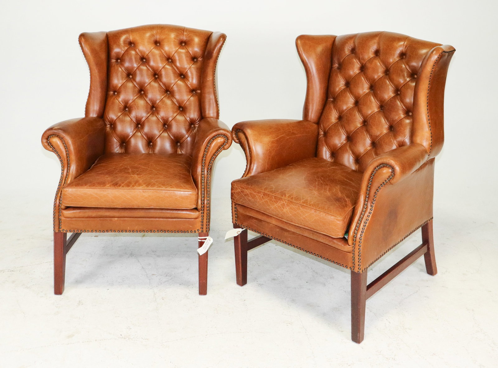 Pair of Danish Tufted Leather High back Armchairs: A pair of Danish brown leather tufted wingback armchairs. Each chair measure 42 in tall x 34 in x 35 in and a seat height of 19 in.