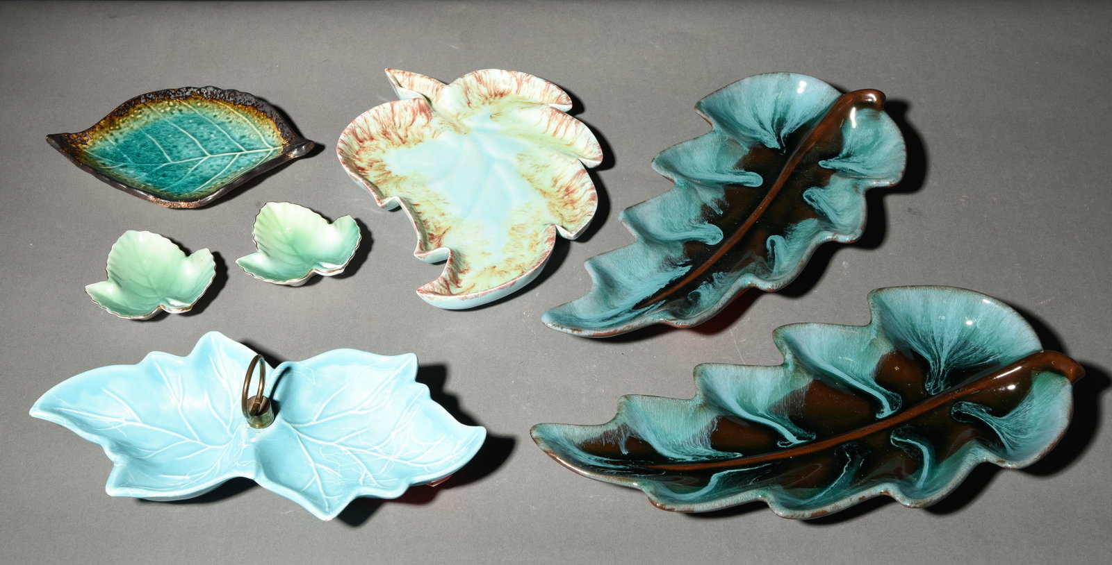 7 Assorted Pottery Leaf Trays / Dishes: 7 Assorted Pottery Leaf Trays / Dishes - Largest is 2 in tall x 14 x 6.5 - Some is marked made in U.S.A, some Canada, Etc.