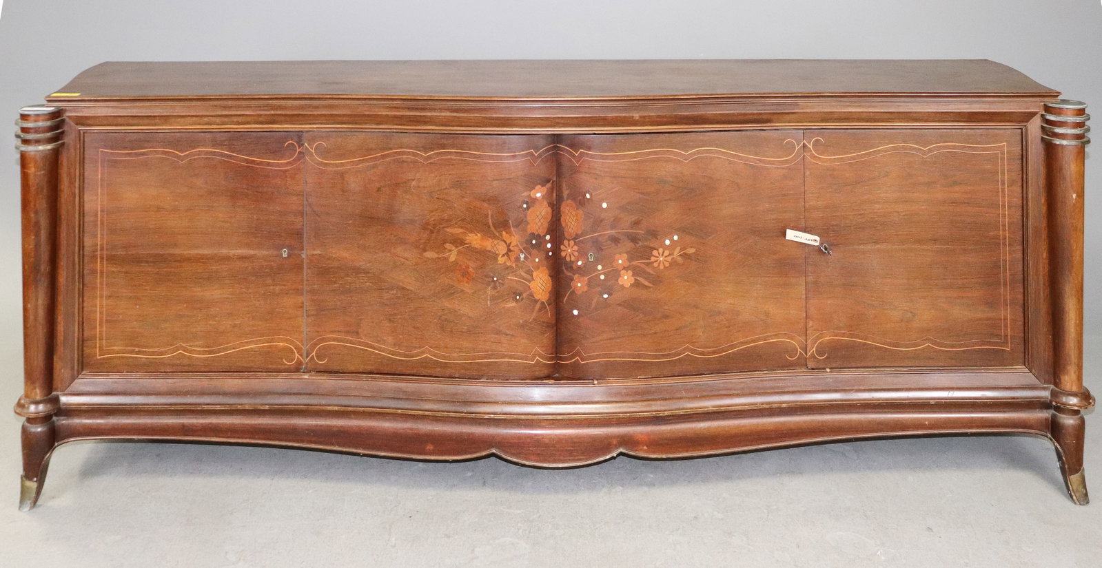 Vintage French Art Nouveau Style Inlaid Serpentine Sideboard: Elegant vintage French-style sideboard or credenza featuring a long serpentine-form case with four cabinet doors and beautifully figured wood grain. The center doors are decorated with floral marquetr
