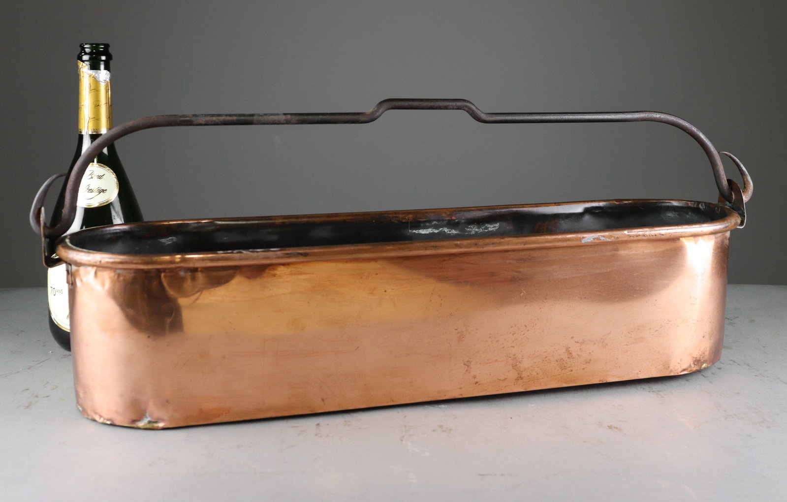 French Copper Fish Poacher with Iron Handle: French copper fish poacher featuring an elongated oval form with fitted wrought iron swing handle and loop handles at the ends. Interior retains a darkened aged surface with attractive patina througho