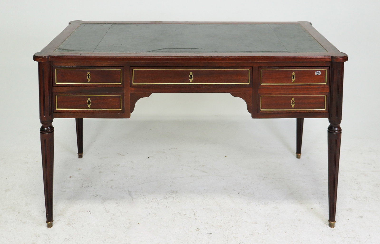 French Louis XVI Style Mahogany Green Leather Bureau Plat Desk: French Louis XVI style mahogany bureau plat desk with inset green leather writing surface and gilt-tooled border. Features multiple drawers with brass trim, faux drawer detailing to the reverse, and p