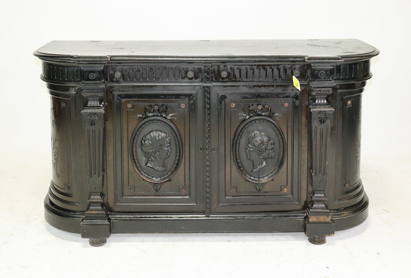 French Ebonized Renaissance Revival Carved Sideboard Cabinet: French ebonized wood sideboard or cabinet with elaborate Renaissance Revival detailing. Features a shaped top, fluted architectural columns, carved frieze and two paneled doors decorated with raised c
