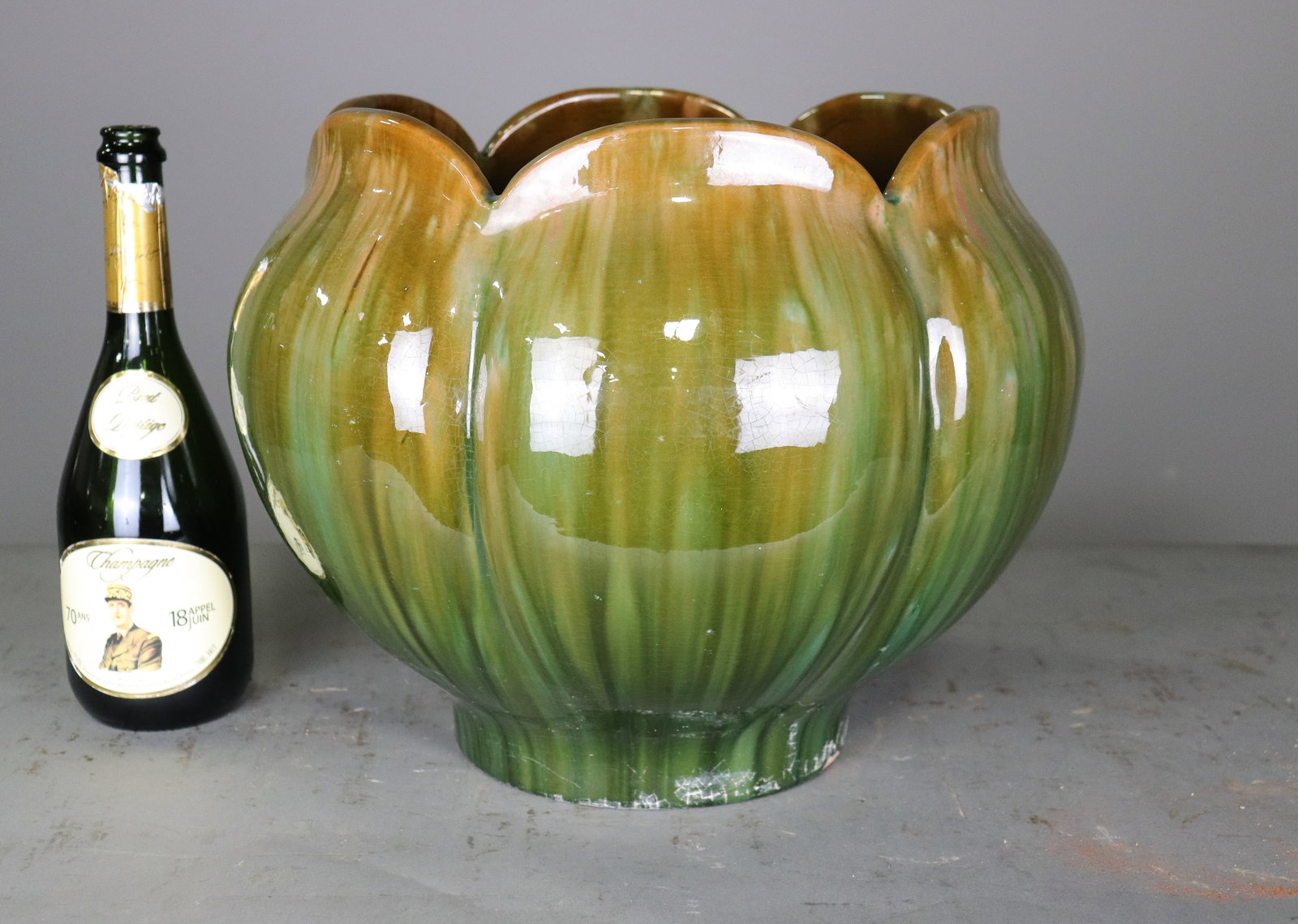 Green Glazed Ceramic Flower Petal Jardiniere: Decorative ceramic jardiniere with a sculptural overlapping flower petal form and glossy green and amber glaze. Raised on a short circular foot. 12.25 in tall x 15.5 x 15.5