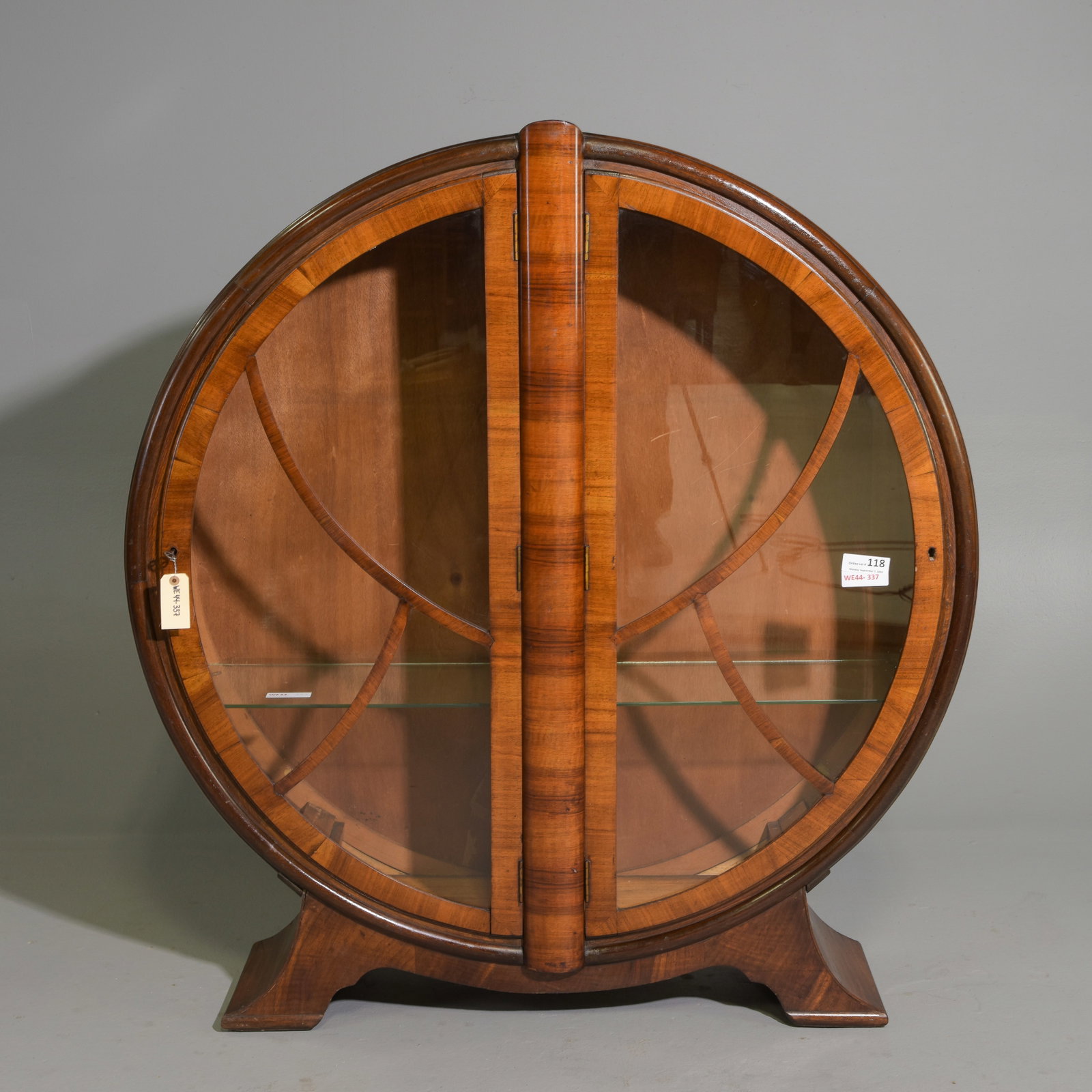 Art Deco Walnut Circular Display Vitrine Cabinet: Art Deco Walnut Circular Display Vitrine Cabinet with striking geometric symmetry, a bold circular silhouette and stylized wooden astragal bars framing the glass doors. This is a beautiful representat