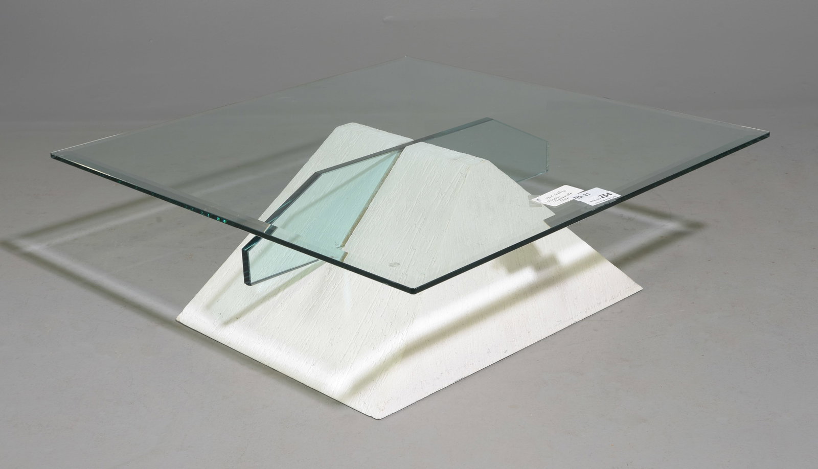 Postmodern Sculptural Glass Top Coffee Table: Sculptural postmodern coffee table featuring a textured white plaster or gesso finish over a wood or composite pyramidal base. Intersecting cut-glass panels rise through the base to support a square c