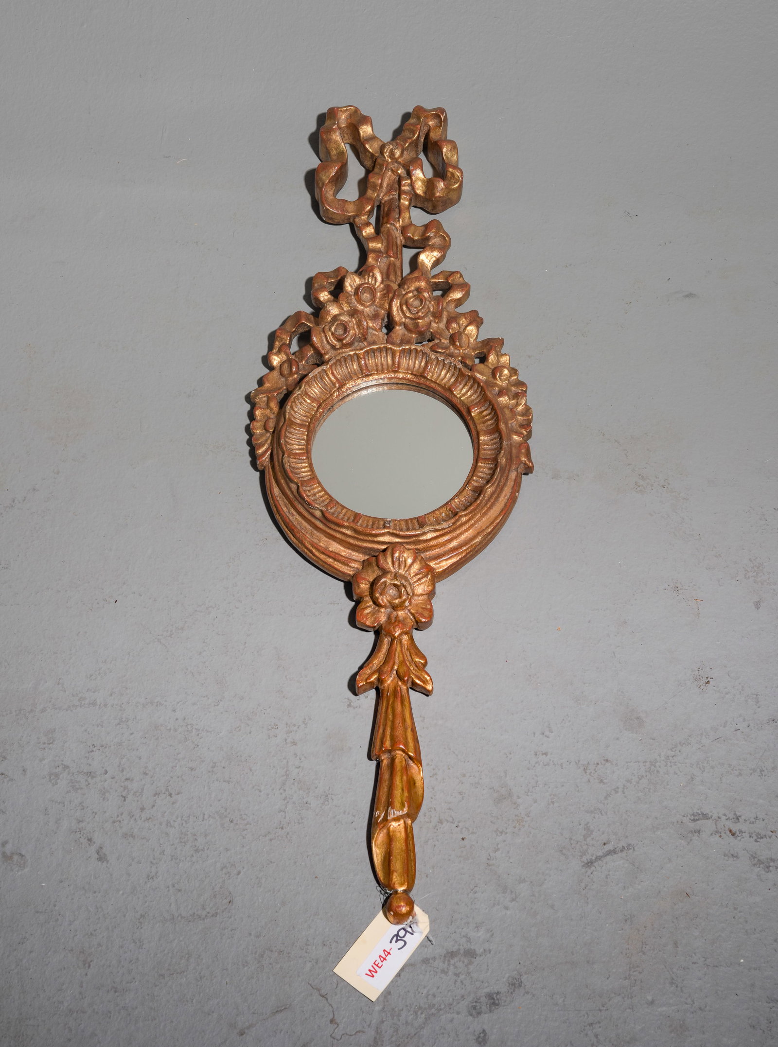 Italian Rococo Style Gold Wall Mirror: Italian Rococo Style Gold Wall Mirror with an elongated vertical silhouette accented by flowing ornamental ribbon bow at the crest - 33.5 in tall x 10.5 x 2