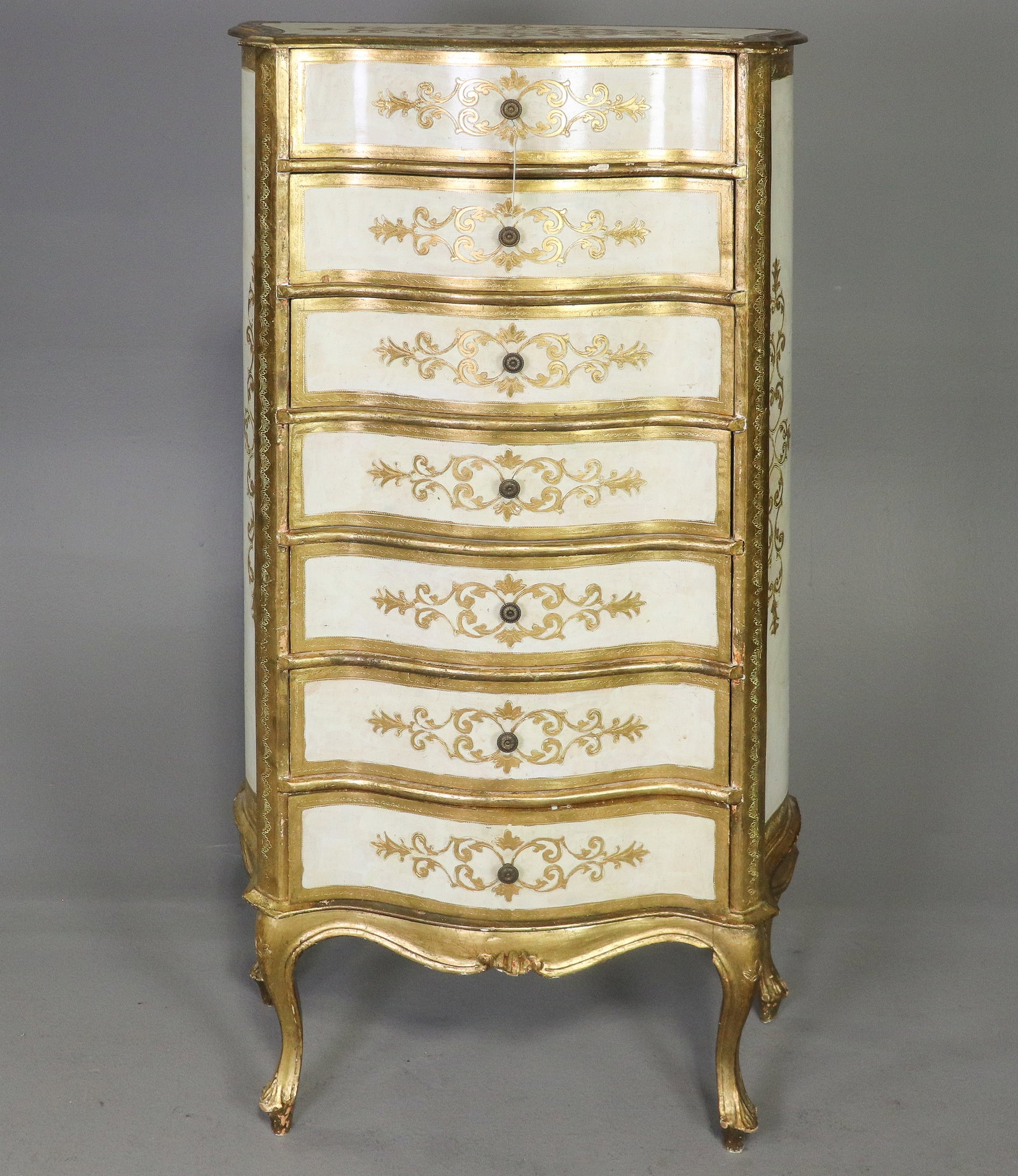 Italian Florentine Style Gilt Painted 7 Drawer Lingerie Chest: Italian Florentine style tall seven drawer lingerie chest featuring a shaped serpentine front with gilt molded edges and hand-painted scrolling foliate decoration. Cream painted case with extensive gi